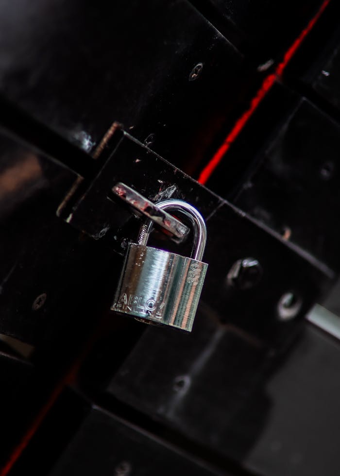 Close-up view of a metal padlock securing a dark door latch, symbolizing safety and protection.